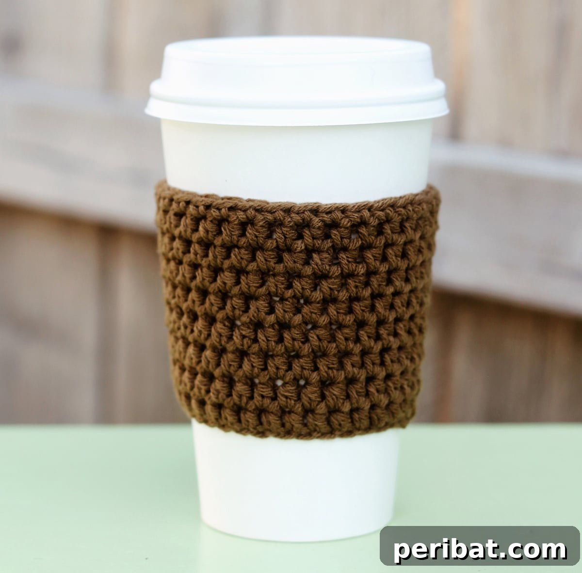 Charming crocheted coffee sleeve in vibrant colors, adding comfort and style to your cup