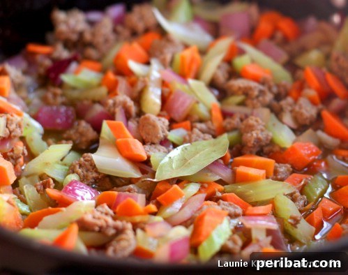 A baking dish filled with the layered turkey and vegetable filling, topped with mashed potatoes, ready for the oven