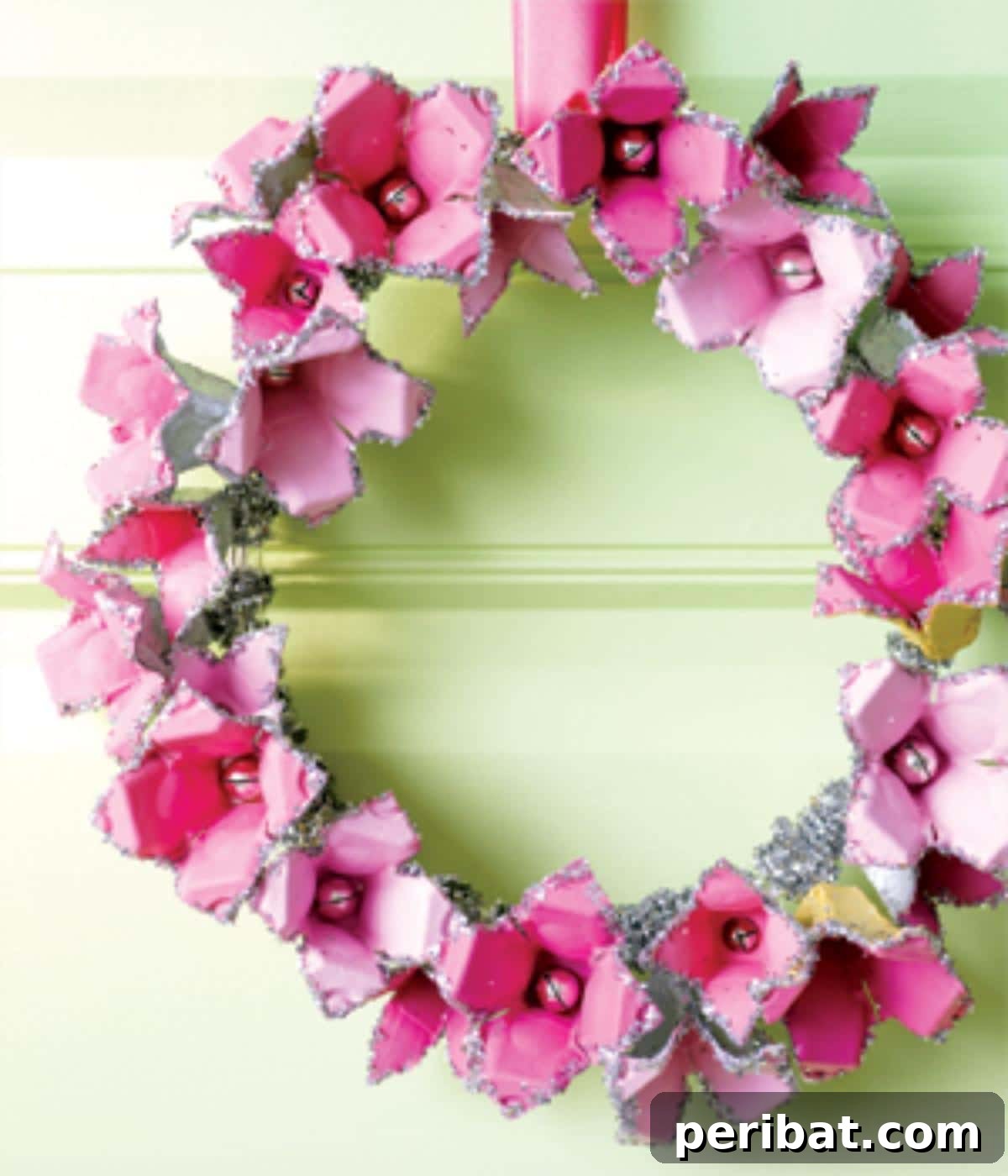 35 Mind-Blowing Creations from Empty Egg Cartons 18 A charming wreath adorned with pink egg carton flowers, each featuring sparkly edges, creating a festive and elegant decoration.