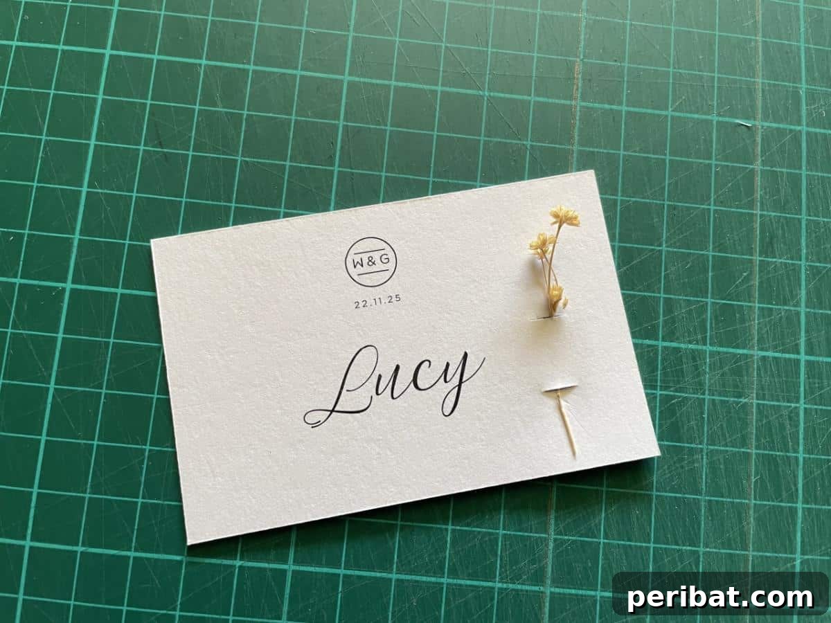 DIY Wedding Place Card With Real Flowers. Features a place card adorned with delicate, fresh flowers, adding a natural and romantic touch to wedding table settings.