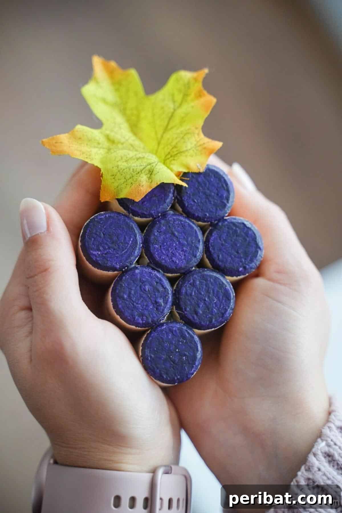 Uncork Your Creativity 50 Wine Cork DIY Projects 3 A close-up view of a rustic grape-painted wine cork decoration, featuring painted purple grapes and green leaves on natural corks, arranged to resemble a bunch of grapes.