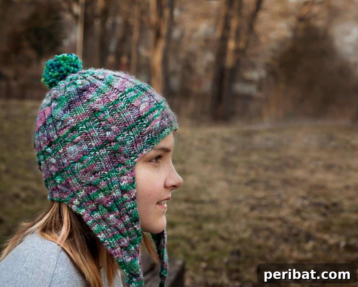 32 Cozy Ear Flap Hat Knitting Designs 30 The Elysium Cabled Earflap Hat, showcasing intricate cable patterns that form a beautiful snowflake design.