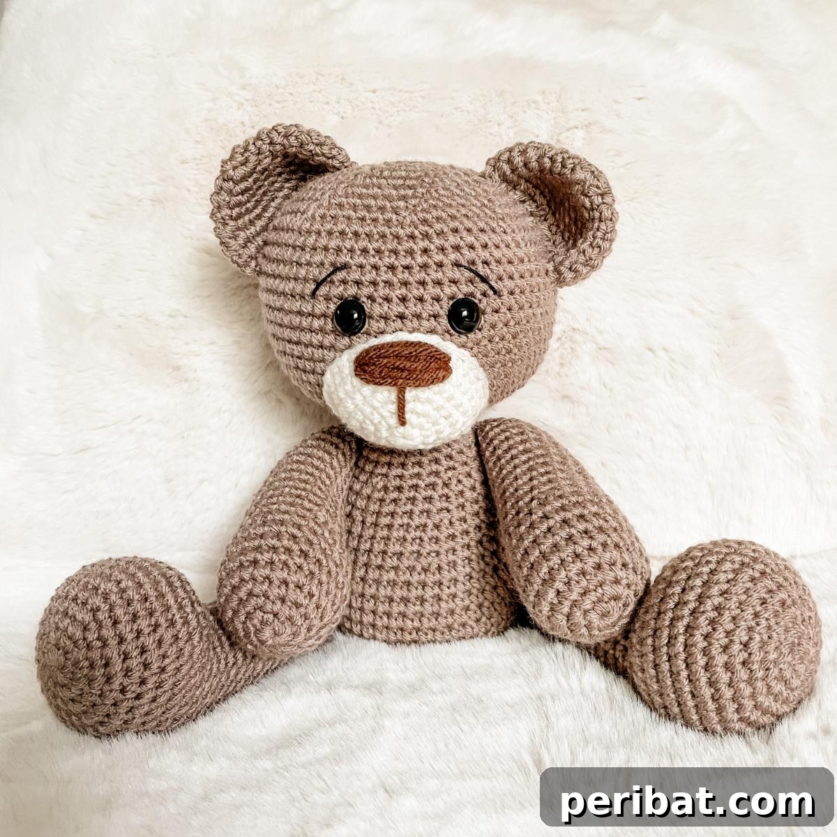 A cute crochet teddy bear in an ivory color with a sweet expression.