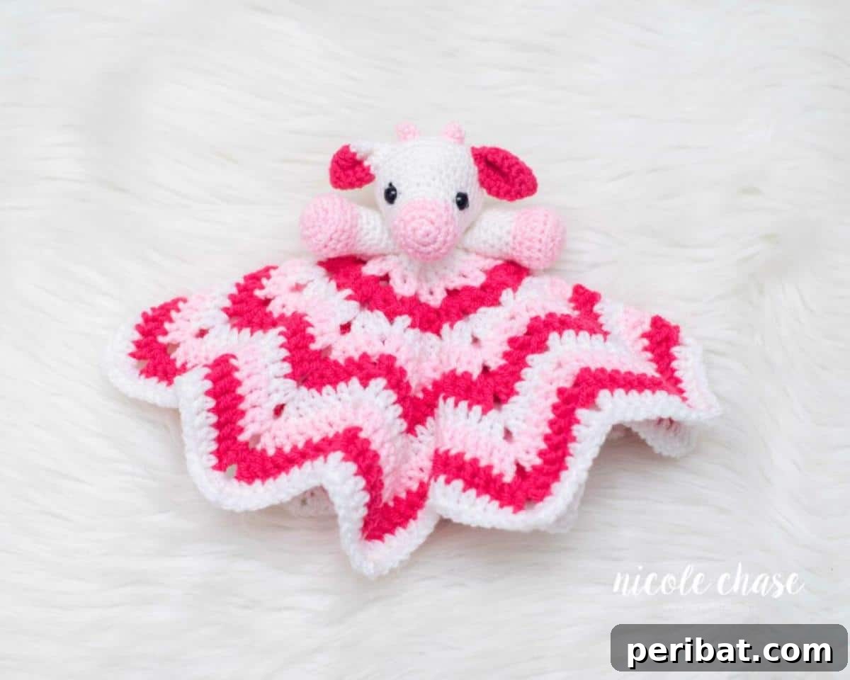A sweet Hug Me Cow Lovey crochet pattern, featuring a small cow head attached to a blanket.