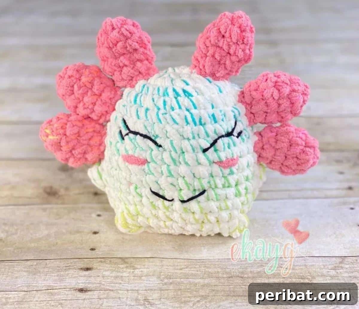 A smiling, puffy amigurumi Puffy Stuffy Axolotl crochet toy in pink.