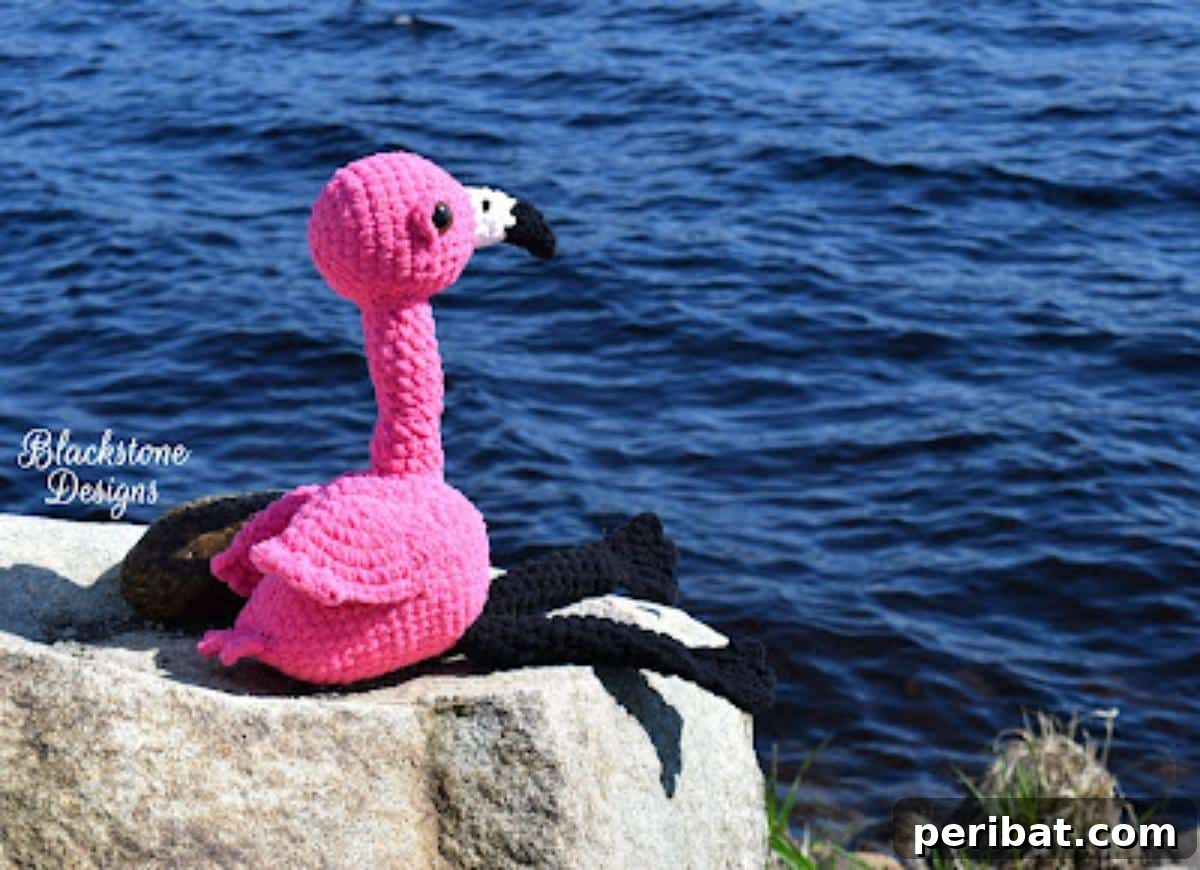 A graceful pink stuffed flamingo crochet toy with long legs and a curved neck.