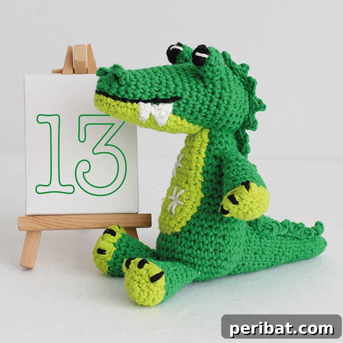 A friendly-looking green amigurumi crochet crocodile toy.