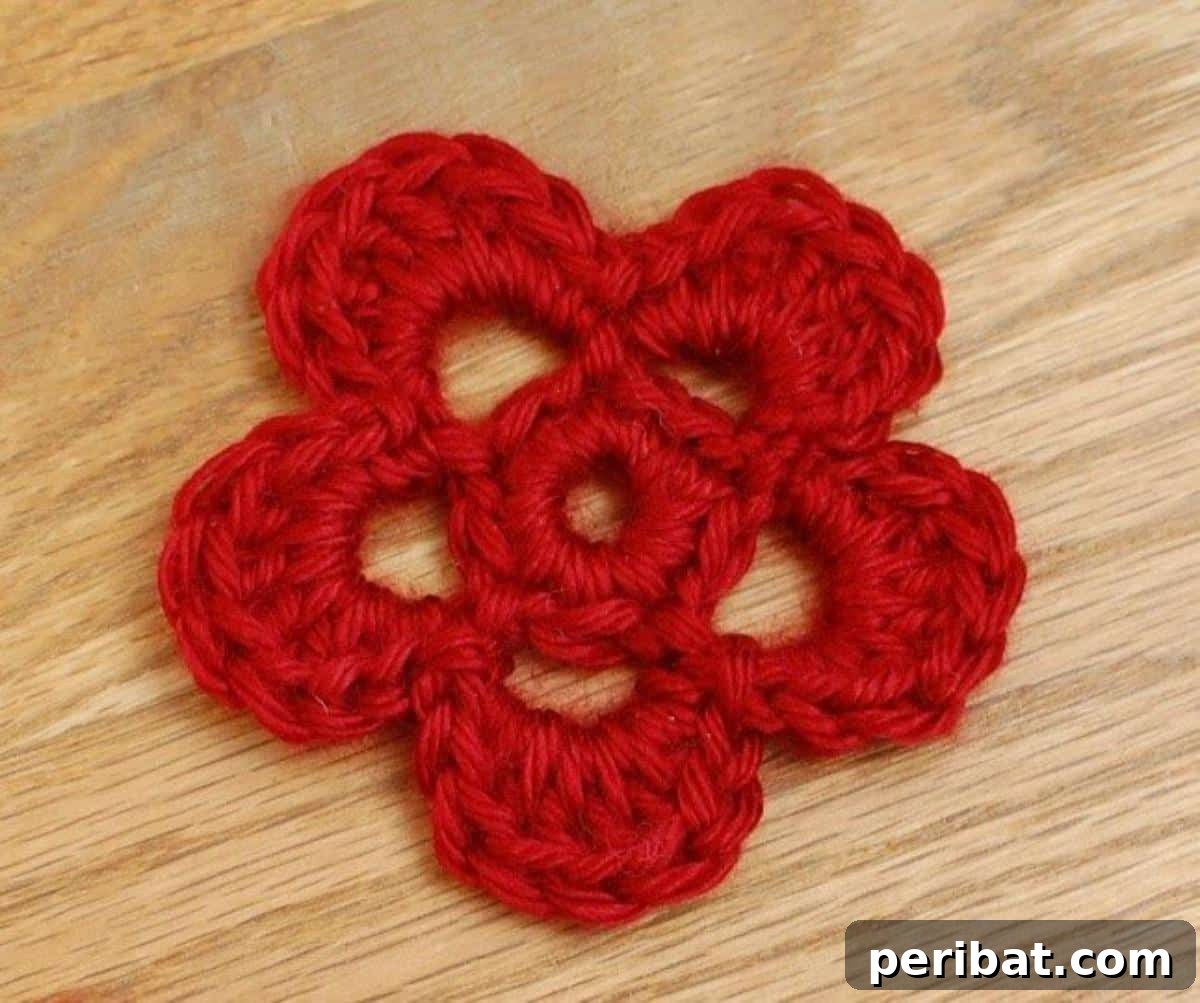 A delicate sweet and simple crochet flower in soft pink, featuring gentle, rounded petals.