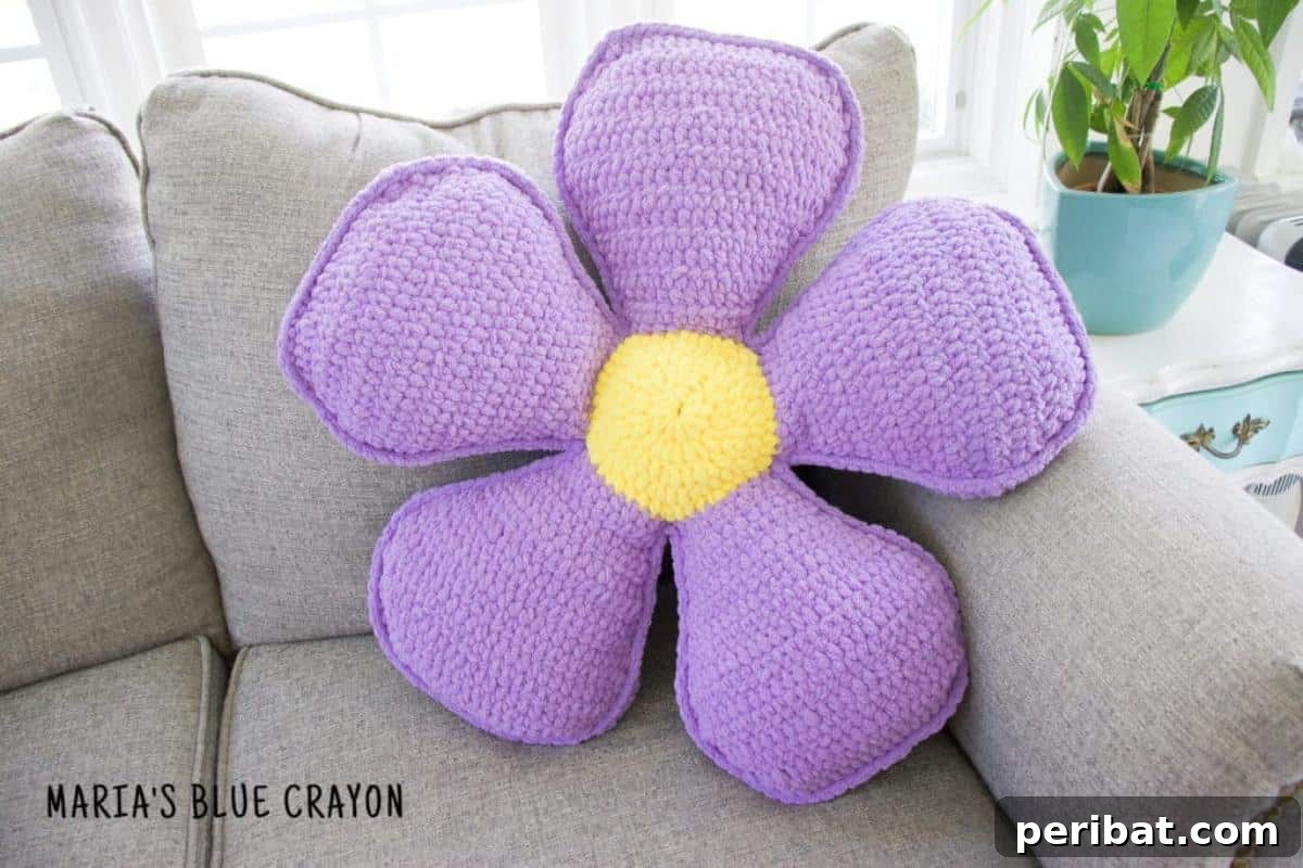 A cozy crochet flower pillow, designed with a large, soft floral motif for comfort and style.