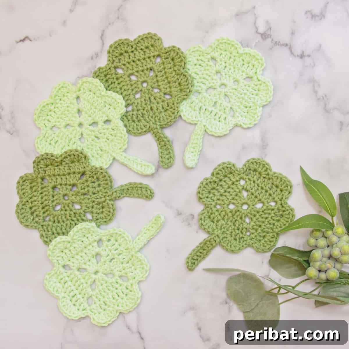 34 Inspiring Crochet Coaster Patterns 7 A collection of shamrock-shaped crochet coasters in various shades of green, ideal for St. Patrick's Day or nature themes.