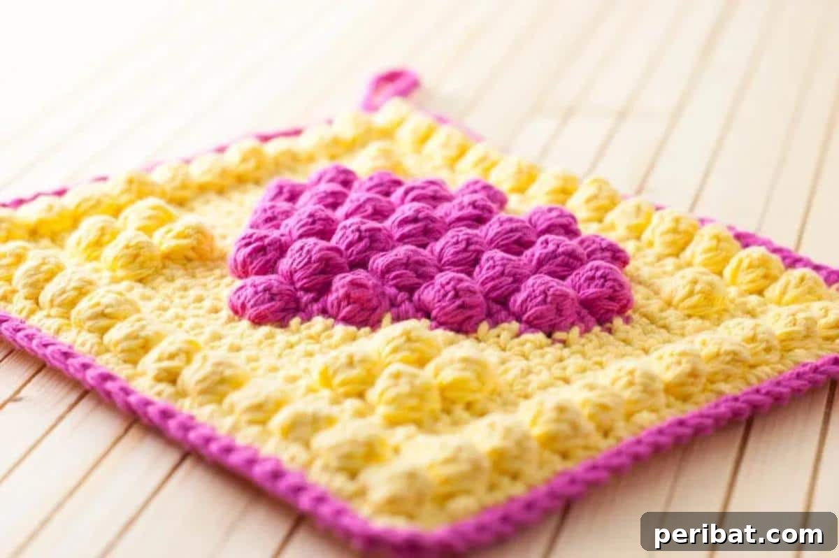 A charming bobble heart potholder in a cheerful color, featuring a raised, textured heart design that adds a sweet, personal touch.