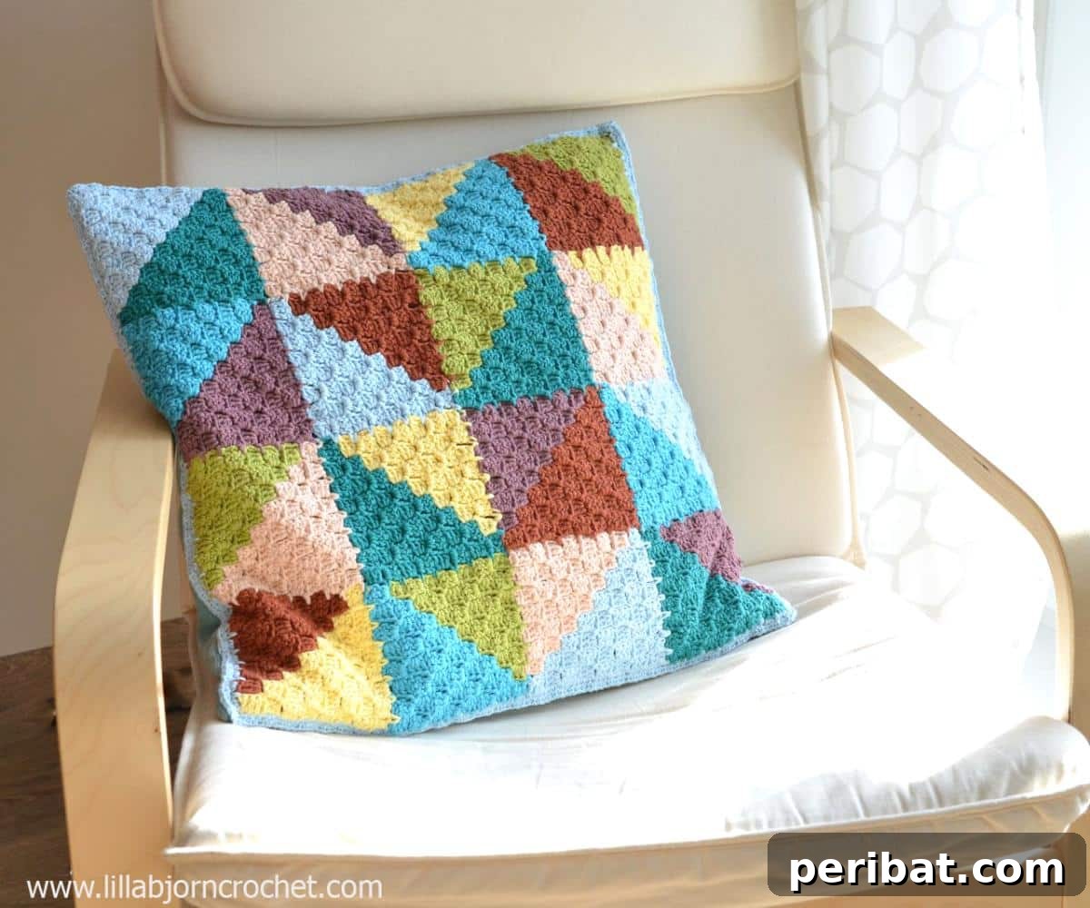 40 Creative Crochet Pillow Projects 10 A charming pastel triangles crochet pillow, crafted with a corner-to-corner technique, showcasing soft, interlocking geometric shapes.