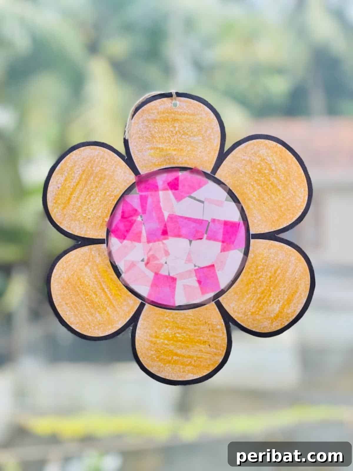 23 Vibrant DIY Tissue Paper Suncatcher Projects 10 A child holding a finished suncatcher made with a free template and tissue paper, featuring a simple geometric design.