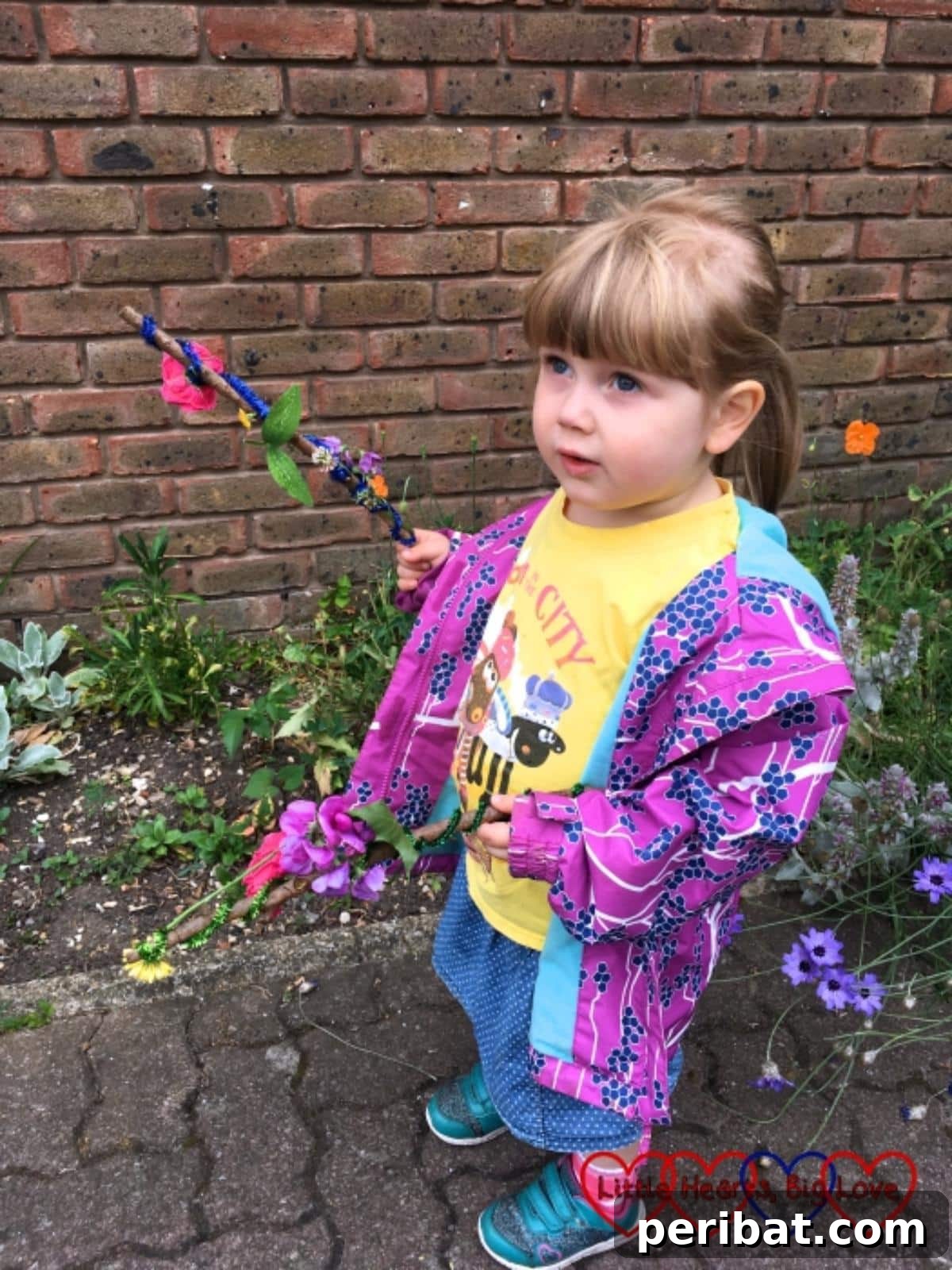 A girl proudly holds two simple nature fairy wands, adorned with natural elements.