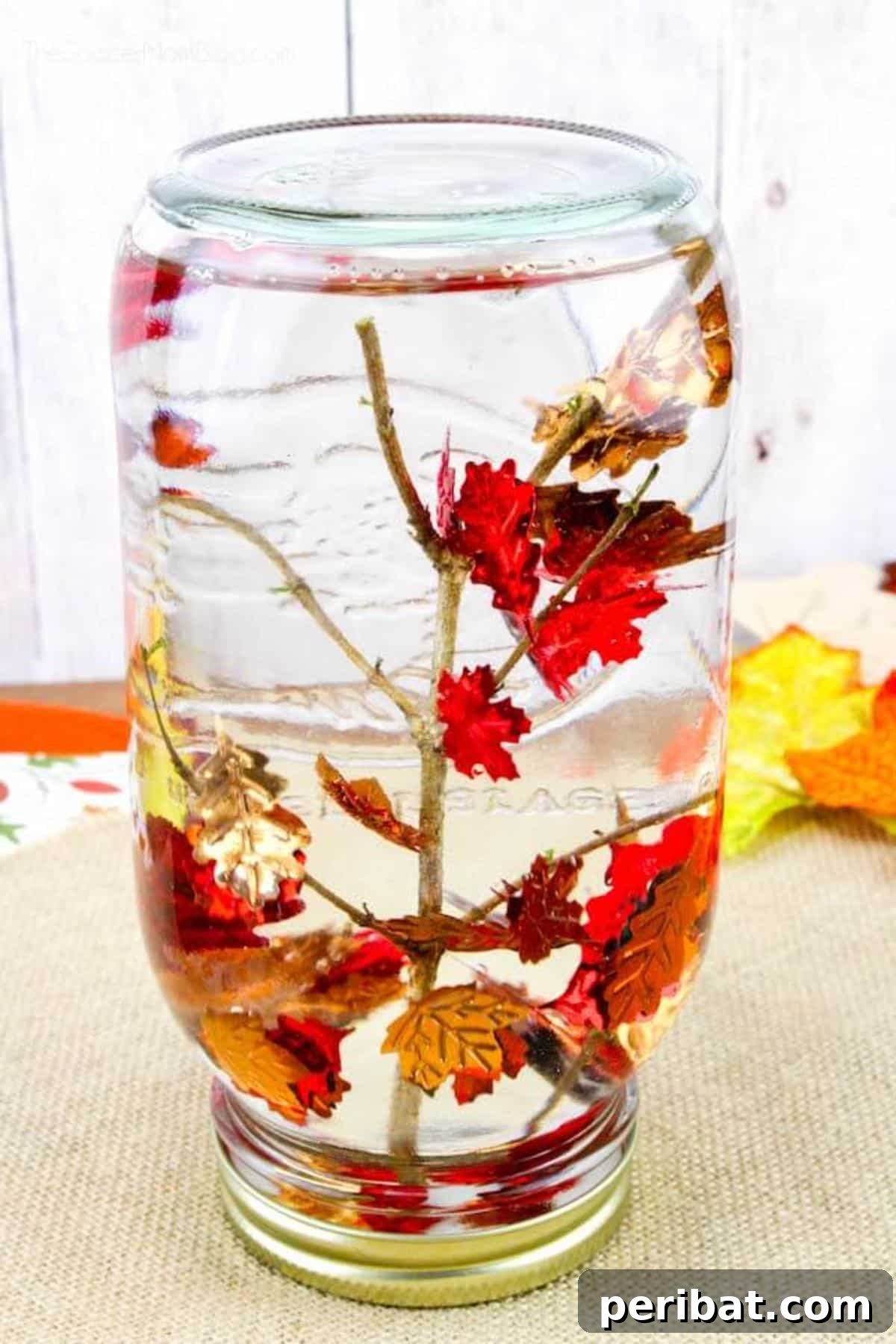 Calming fall snow globe sensory bottle with falling leaves and glitter.
