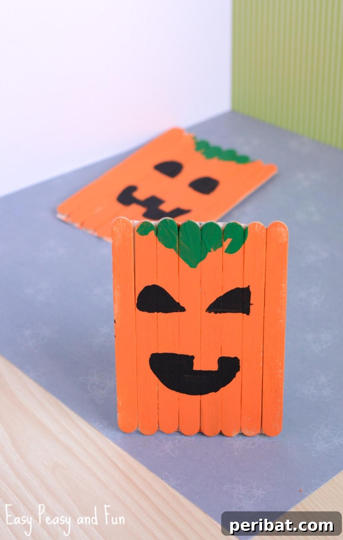 Spooktacular Popsicle Stick Halloween Projects 16 A smiling jack-o'-lantern pumpkin craft made from orange-painted popsicle sticks, featuring a green stem and black facial features.