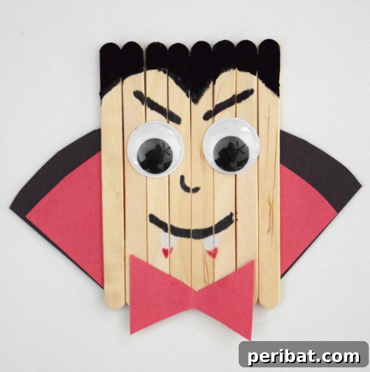 Spooktacular Popsicle Stick Halloween Projects 10 A cute popsicle stick vampire with fangs, a black cape, and a stylized facial expression.
