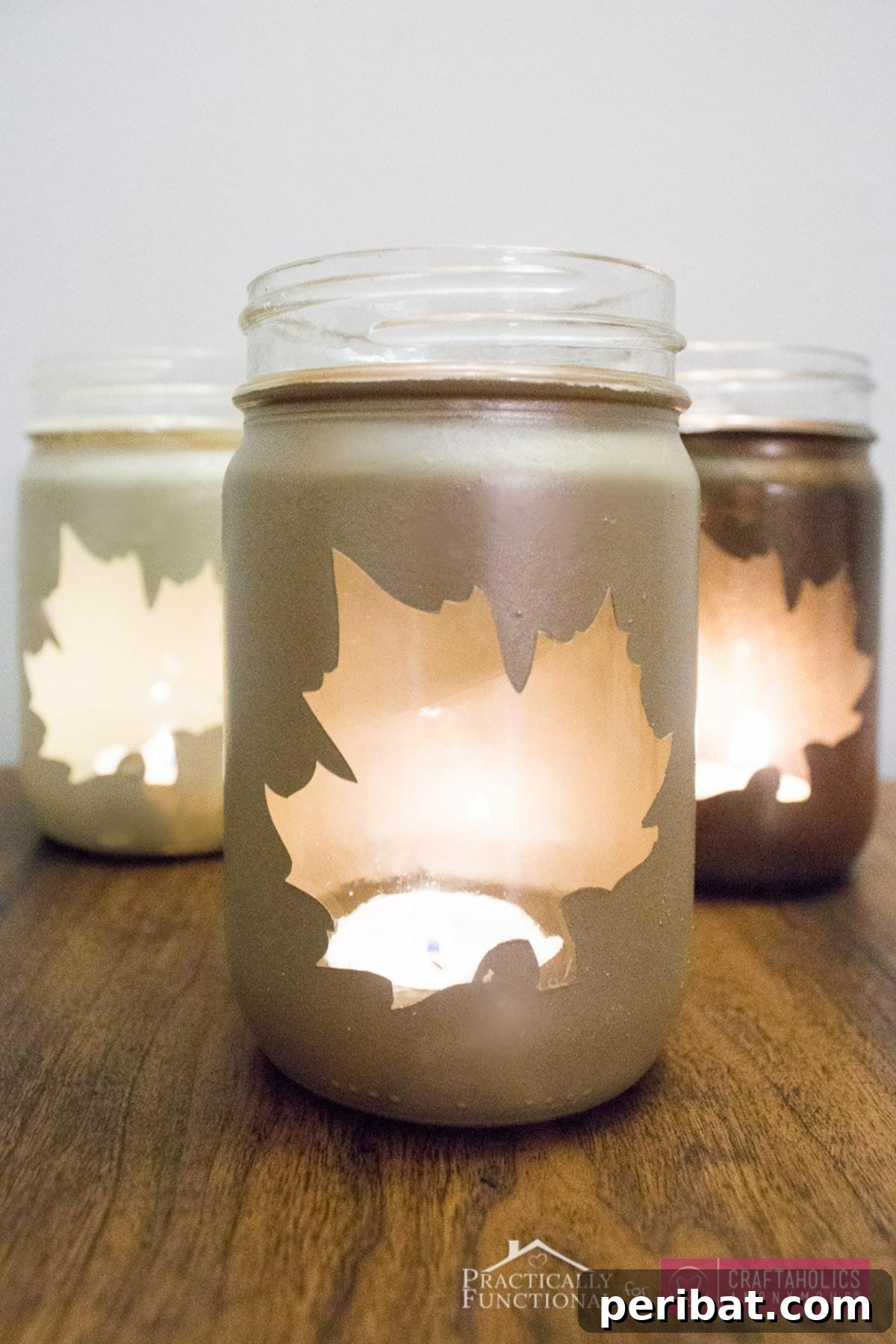Charming DIY fall leaf mason jar luminaries, adorned with painted or decoupaged autumn leaves and glowing warmly from within, perfect for cozy evening ambiance.