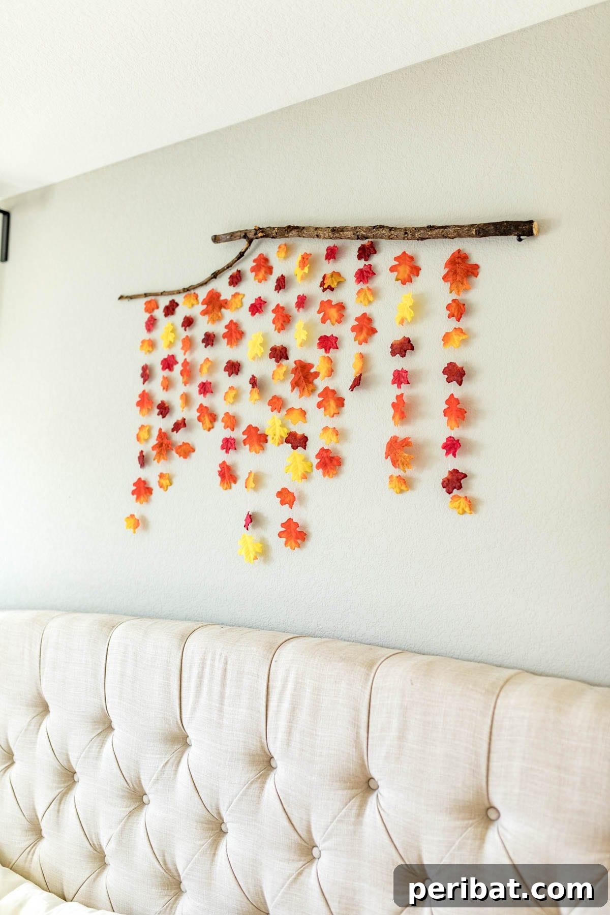 A rustic and artistic DIY fall wall decor piece, featuring colorful autumn leaves delicately suspended from natural sticks with beading string, creating a natural and elegant display.