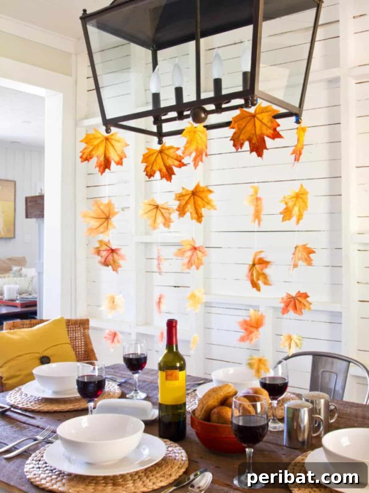 A beautifully decorated autumn table setting enhanced with vibrant fall leaf streamers and natural elements, perfect for a festive Thanksgiving or seasonal meal.