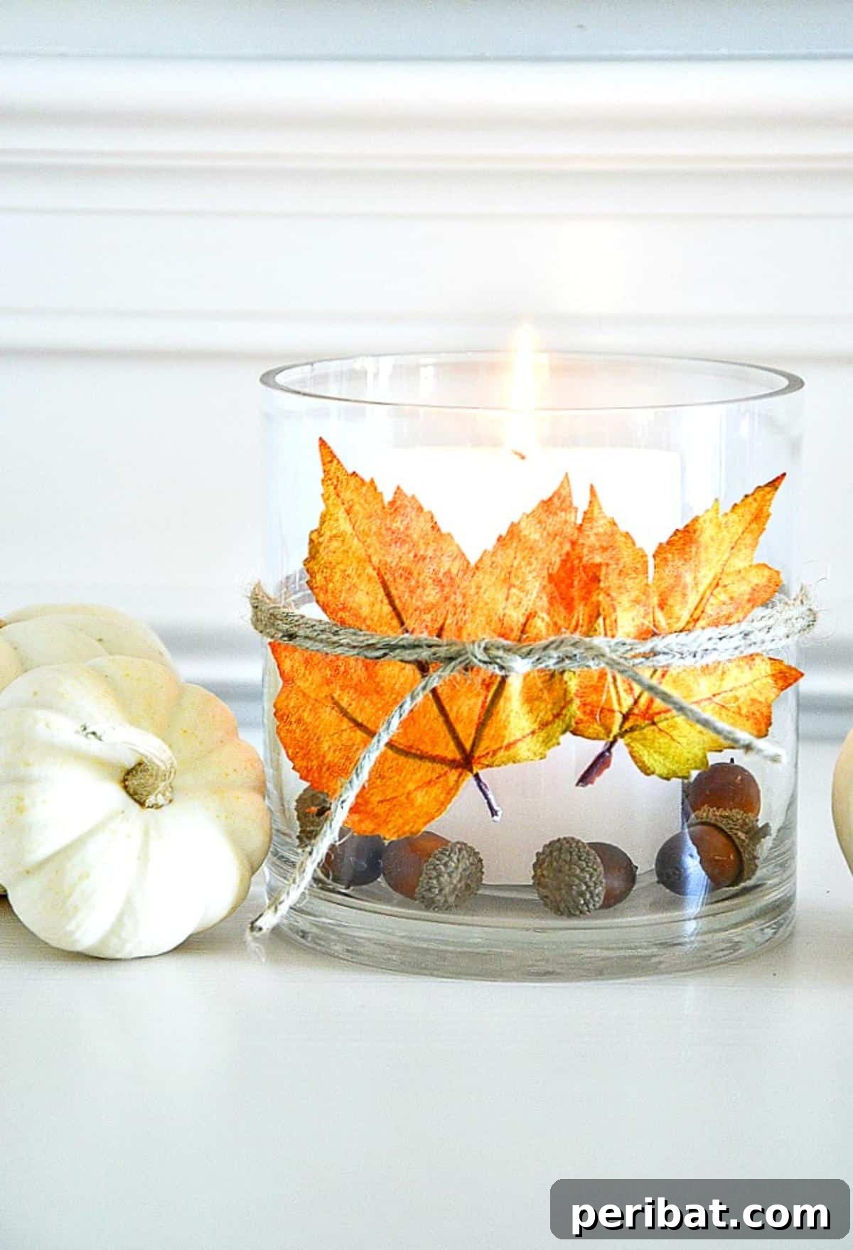 A cozy fall DIY leaf candle holder, created by adhering autumn leaves and twine to a simple glass container, providing a warm, inviting glow for seasonal decor.
