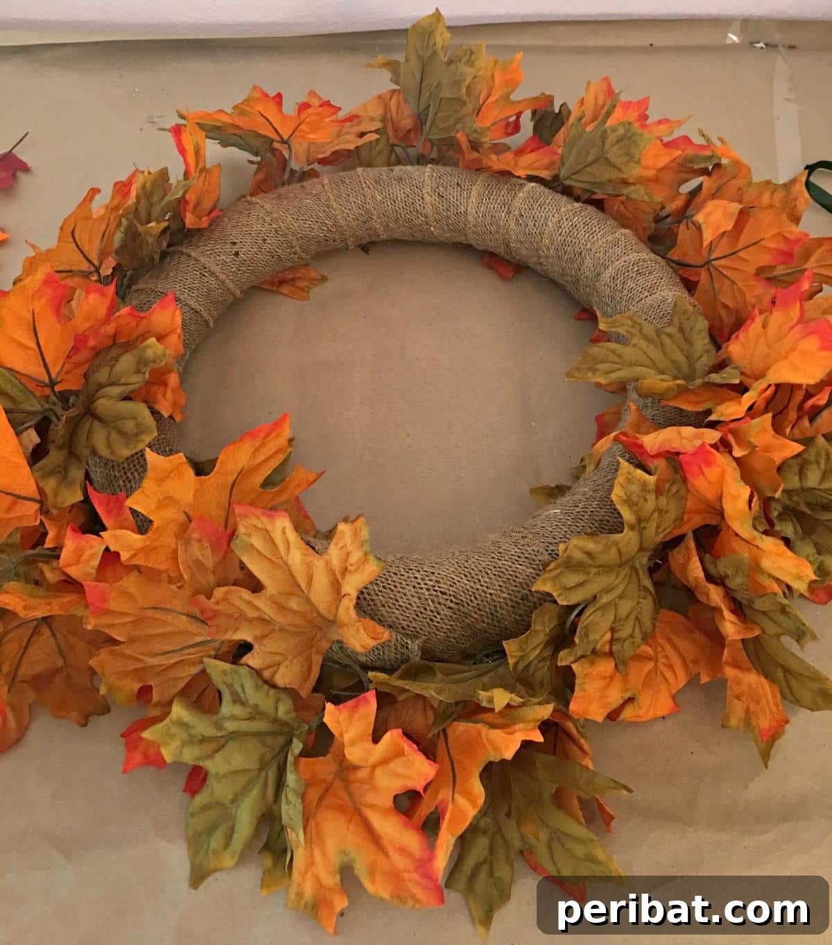 A dynamic and uniquely designed falling leaves wreath, draped horizontally with vibrant artificial autumn leaves, creating a sense of movement and natural beauty for outdoor decor.