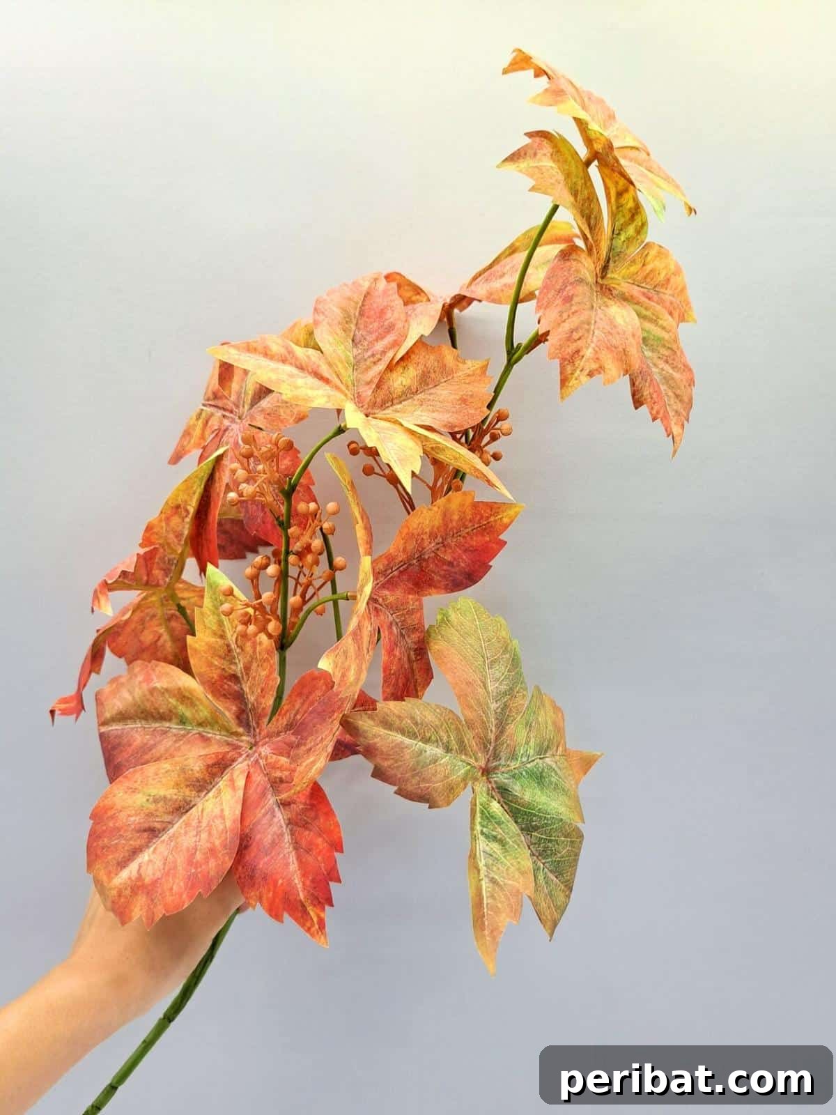 A magnificent fall centerpiece created with large, vibrant autumn tree leaves, branches, and other natural elements, bringing the grandeur of the season indoors.