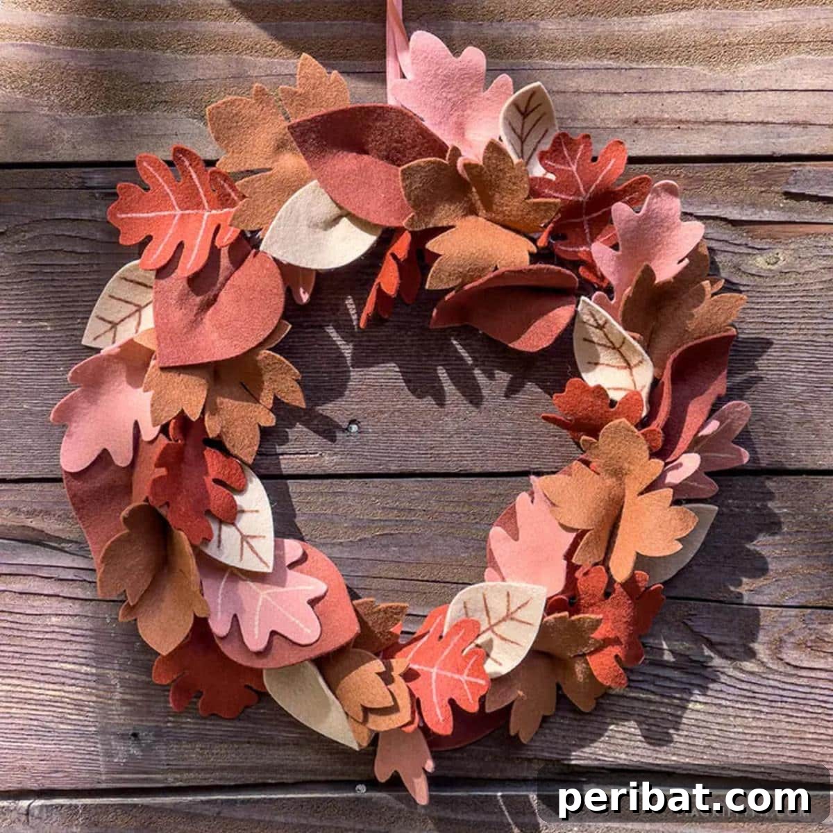 A charming felt fall leaf wreath, featuring various leaf shapes in warm autumnal colors arranged on a simple hoop base, creating a welcoming entryway decor.