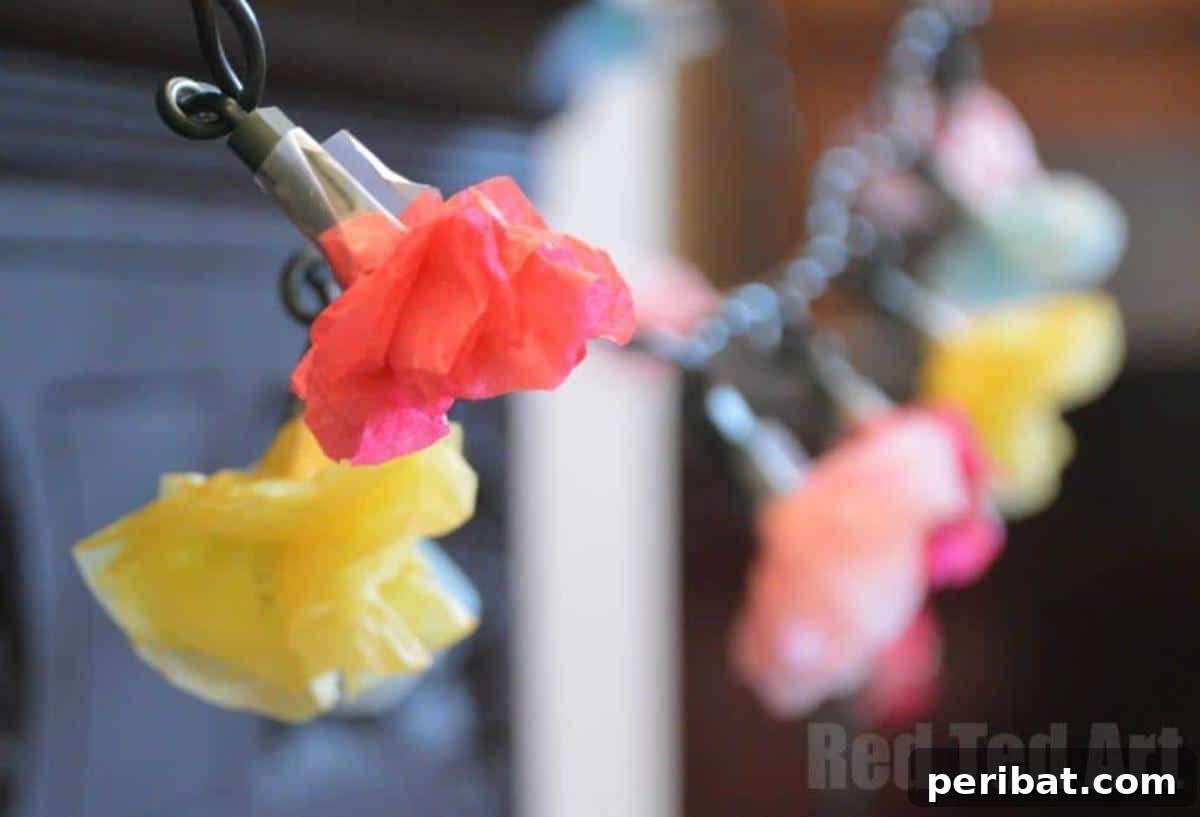 Vibrant Tissue Paper Crafts: 40 DIY Ideas 23 Tissue Paper Flower Fairy Lights. A string of fairy lights adorned with small, colorful tissue paper flowers, creating a soft, whimsical, and enchanting glow.