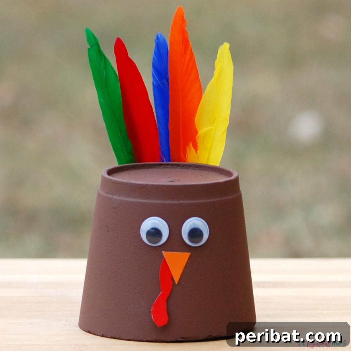 A cute Thanksgiving turkey craft made from a foam cup, feathers, and craft paper.