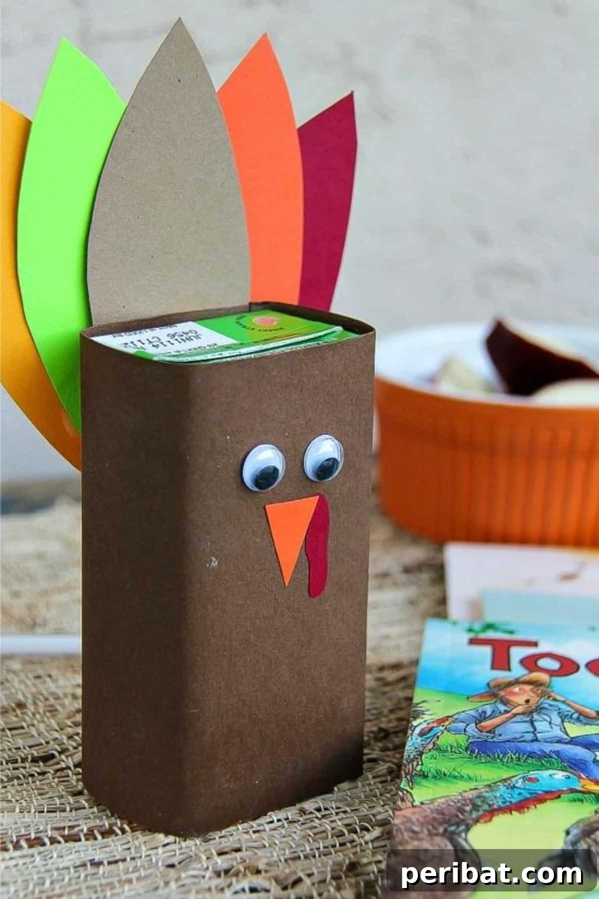 A juice box transformed into a turkey craft with paper feathers and googly eyes.
