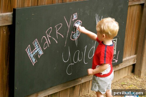 Children drawing and writing on a large outdoor chalkboard