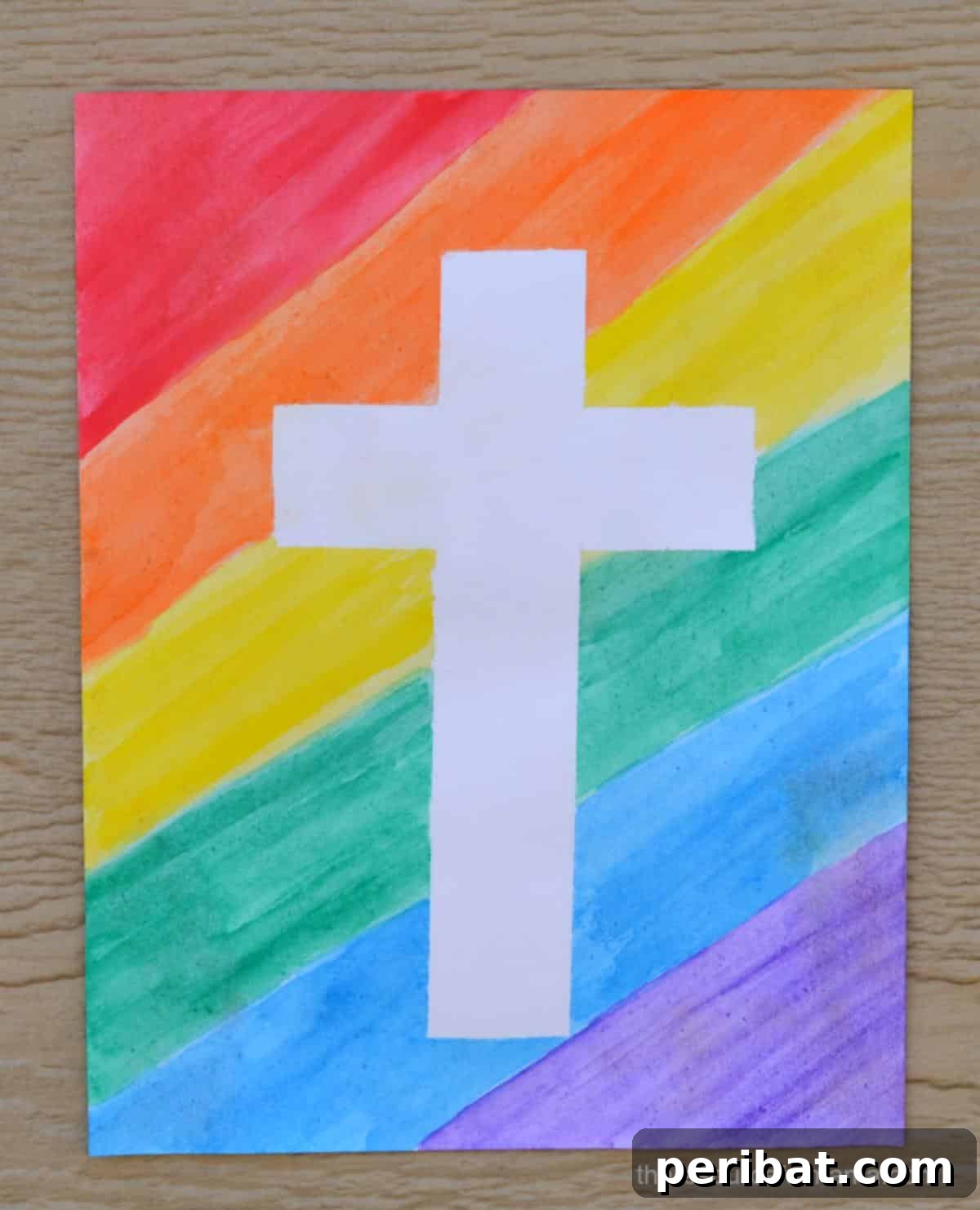 A tape resist cross craft featuring vibrant watercolor paint on card stock.