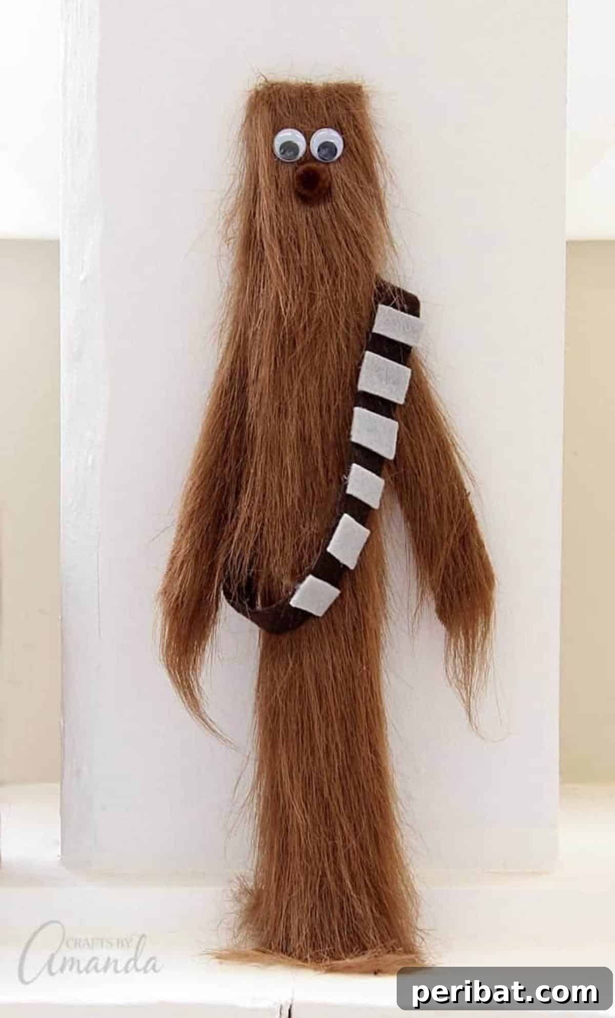 A Chewbacca craft made from a paint stir stick, decorated with brown fur and eyes.