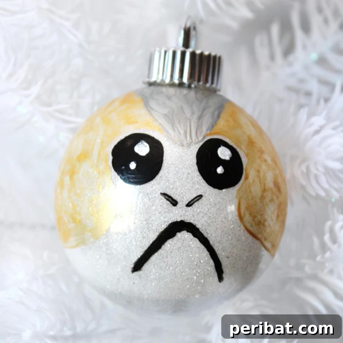 A cute homemade Porg Christmas ornament hanging on a festive tree.