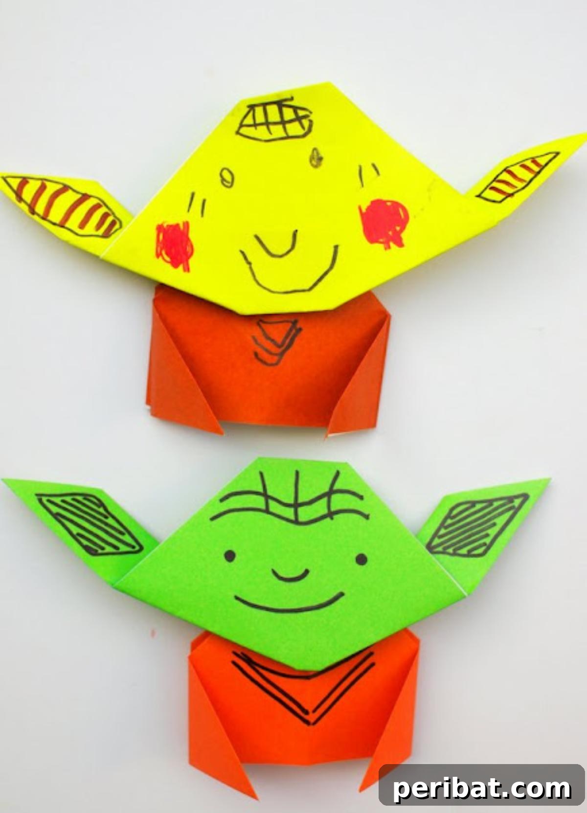 A simple origami Yoda figure, folded from green paper, with drawn eyes and features.