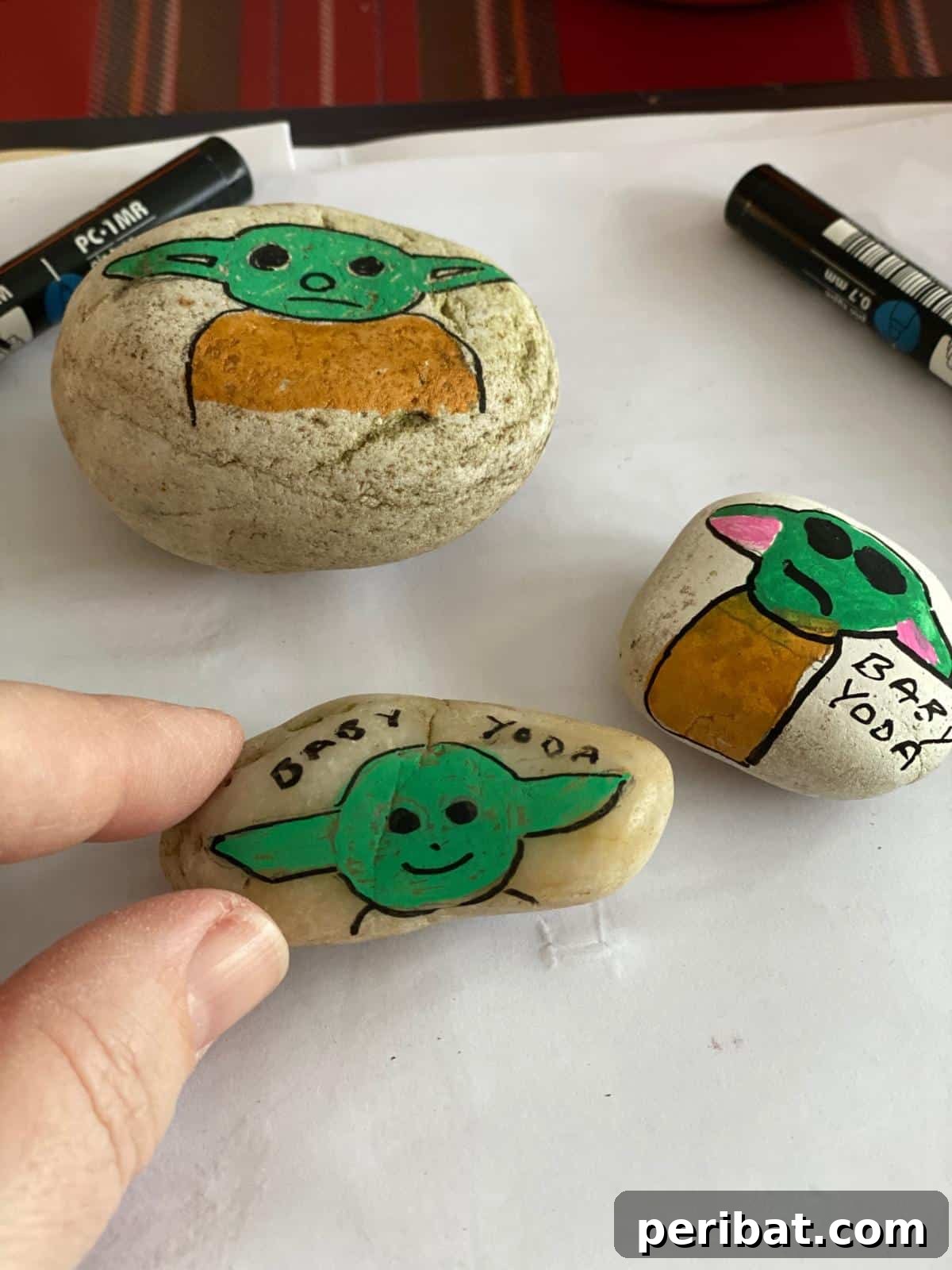 Hand-painted rocks featuring Grogu (Baby Yoda) designs, suitable for garden decorations.
