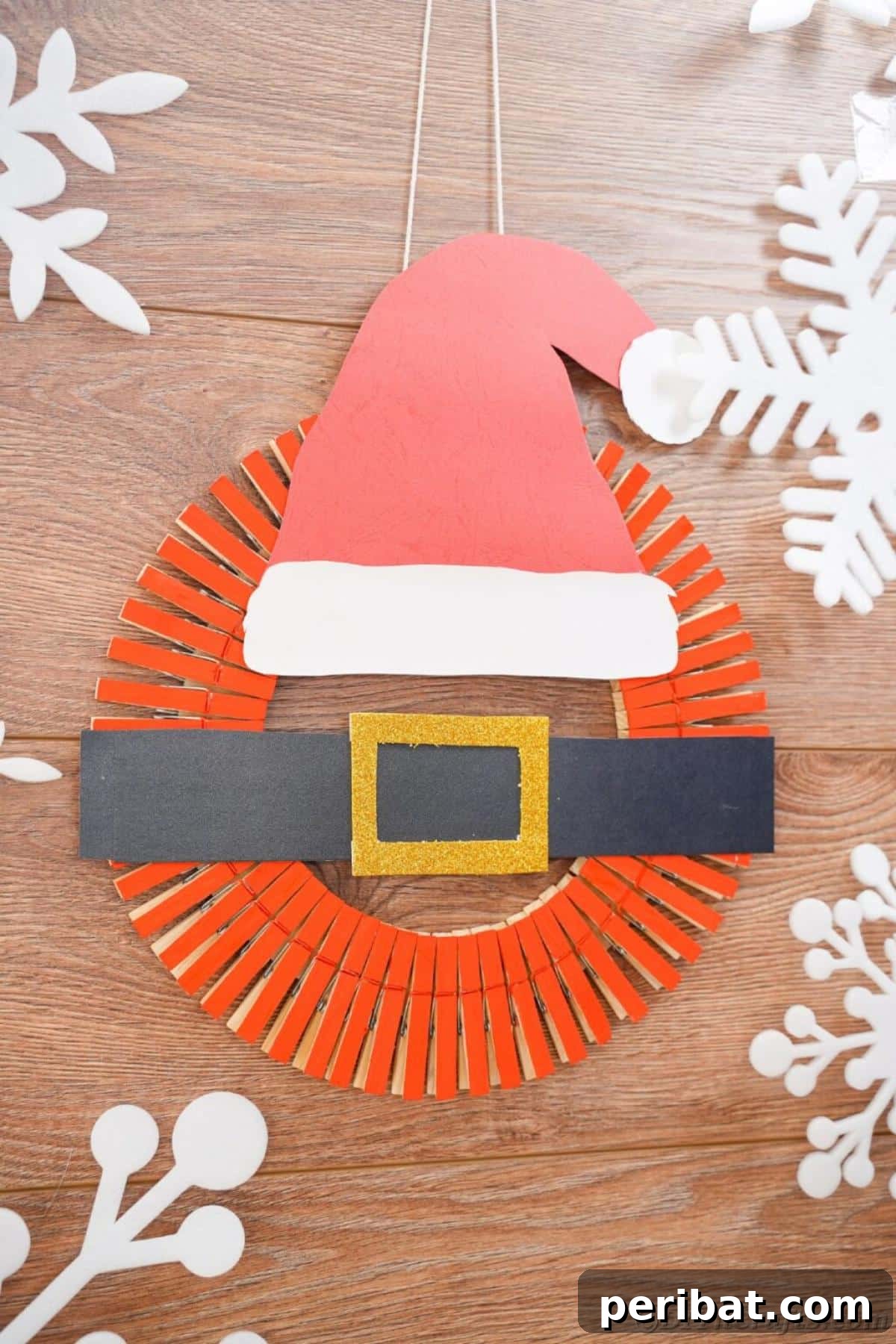 40 Colorful Construction Paper Creations 33 A festive DIY Santa hat wreath Christmas decoration, crafted from red and white fabric to mimic a Santa hat, adorned with green accents.