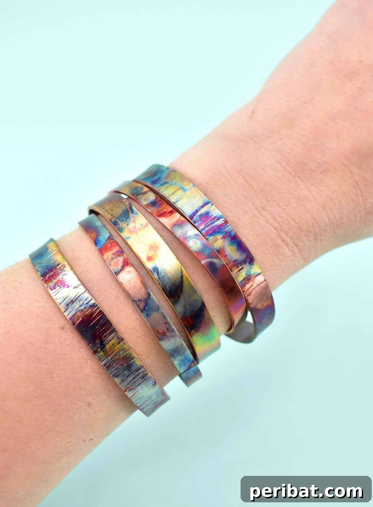 Abstract fire-painted copper bangles with vibrant, iridescent colors.