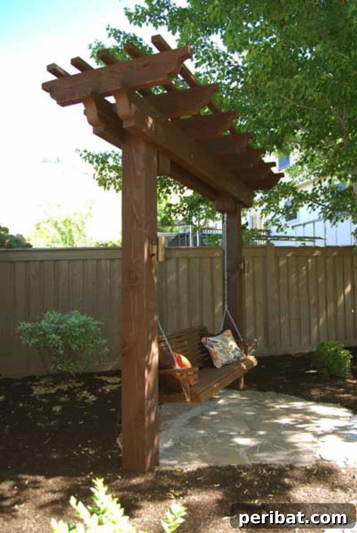 A beautifully designed arbor swing, nestled within a garden, offering shade and comfort beneath a wooden archway.