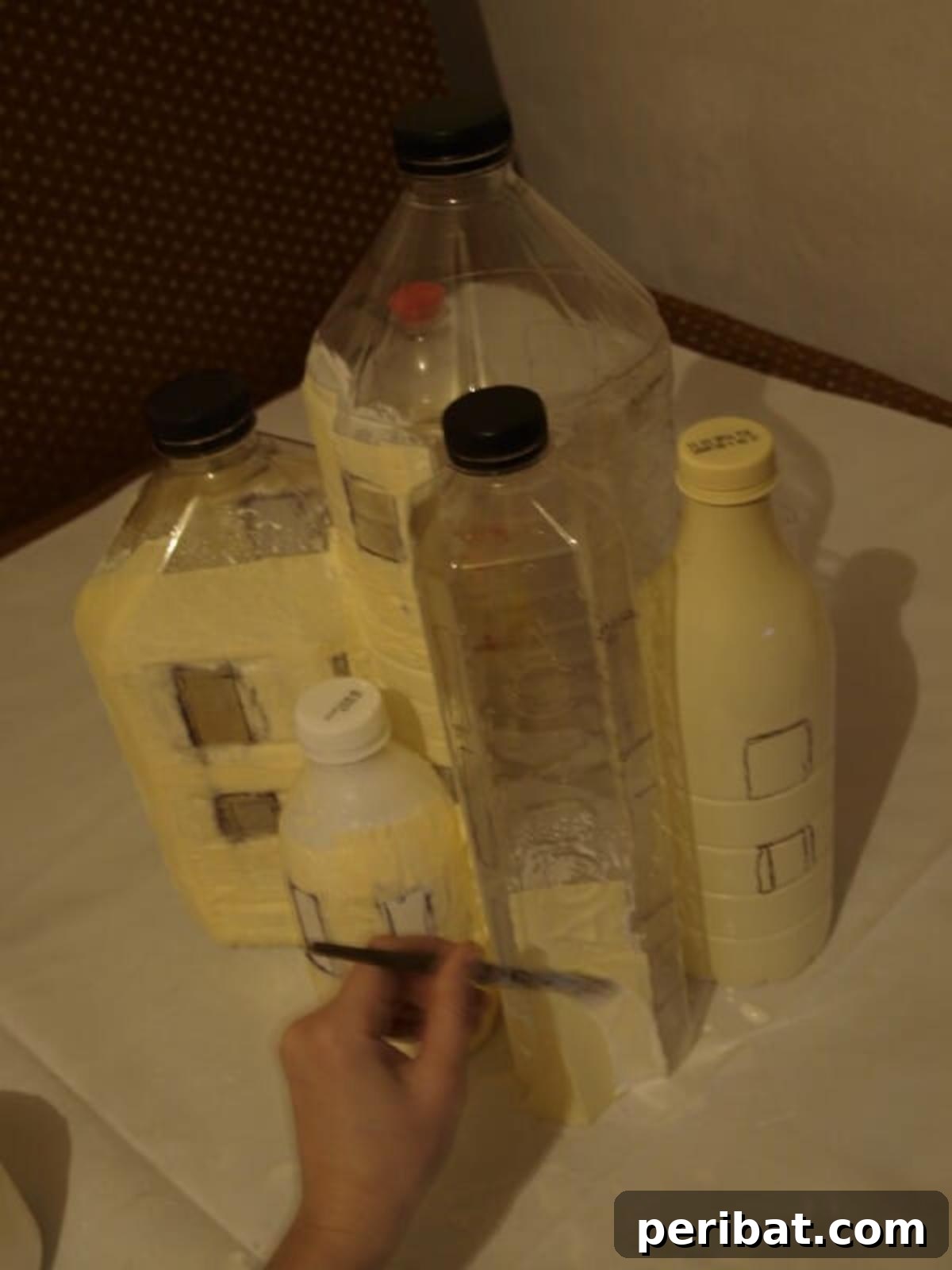 Unleash Magic: Build a Fairy Castle from Plastic Bottles 3 Covering the assembled plastic bottle structure in a generous layer of wood glue, then adhering paper towels to create a rustic, textured surface for the fairy house walls.