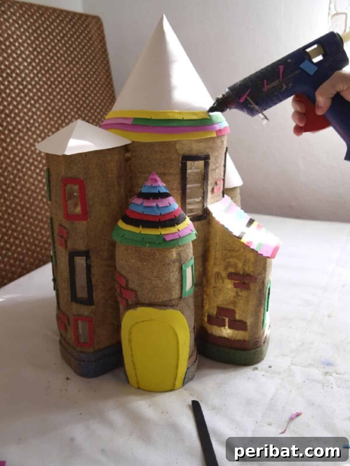 Unleash Magic: Build a Fairy Castle from Plastic Bottles 7 Attaching colorful, notched craft foam strips to the paper cones, layering them meticulously to create realistic and visually appealing roof tiles for the fairy house.