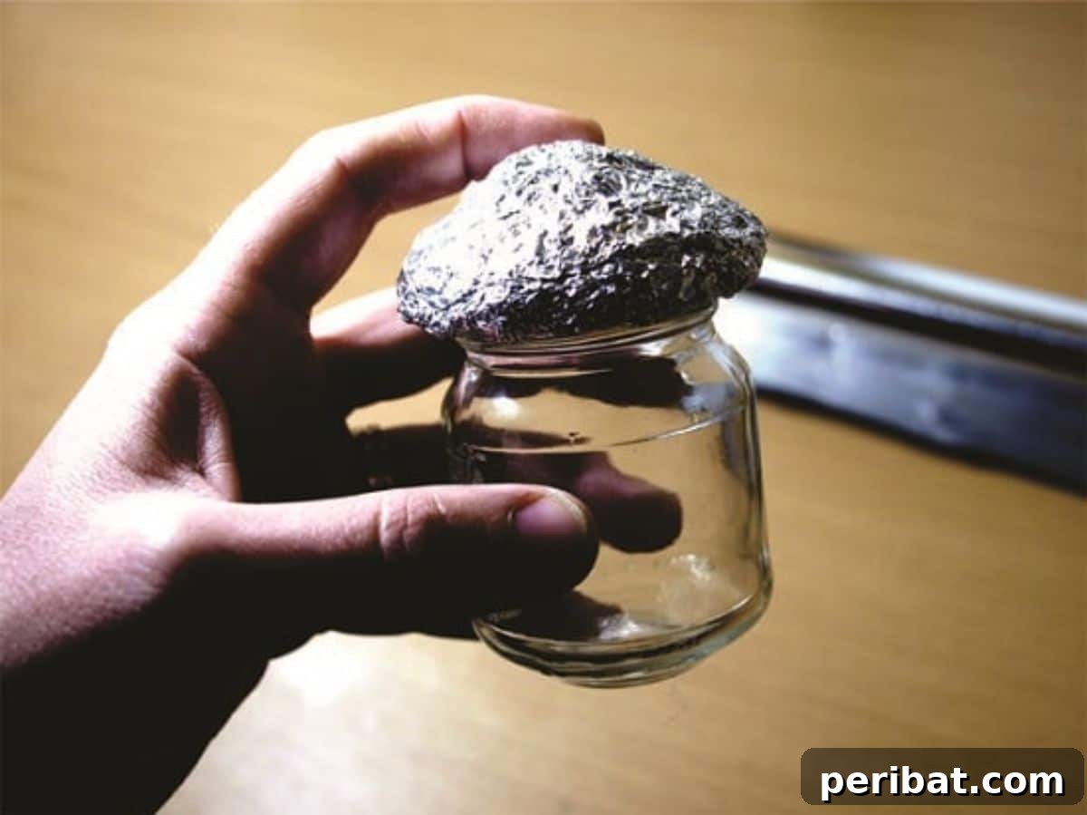 Unlock Whimsy Turn an Old Jar Into a Mushroom Fairy Dwelling 4 Shaping a mushroom cap out of tinfoil to fit on top of the glass jar, preparing it for the clay layer.