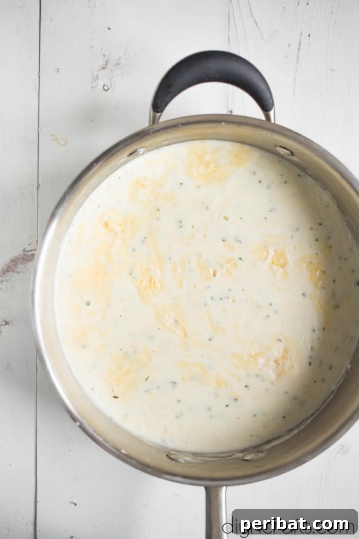 The Ultimate Decadent Mac and Cheese 4 Melted sharp cheese being whisked into a creamy sauce, forming the base for Million Dollar Macaroni and Cheese.