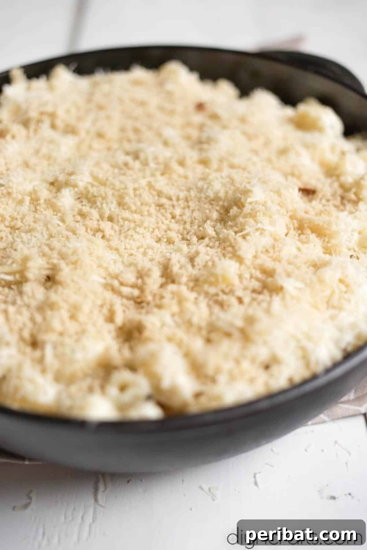 The Ultimate Decadent Mac and Cheese 7 The top layer of mac and cheese sprinkled with a mixture of panko breadcrumbs and grated Parmesan cheese, ready for baking.