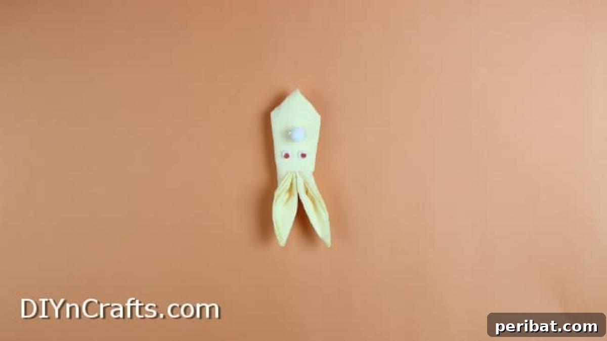 Effortless Adorable Easter Bunny Napkin Place Settings 9 Attaching googly eyes and a pom-pom nose to the finished origami bunny.