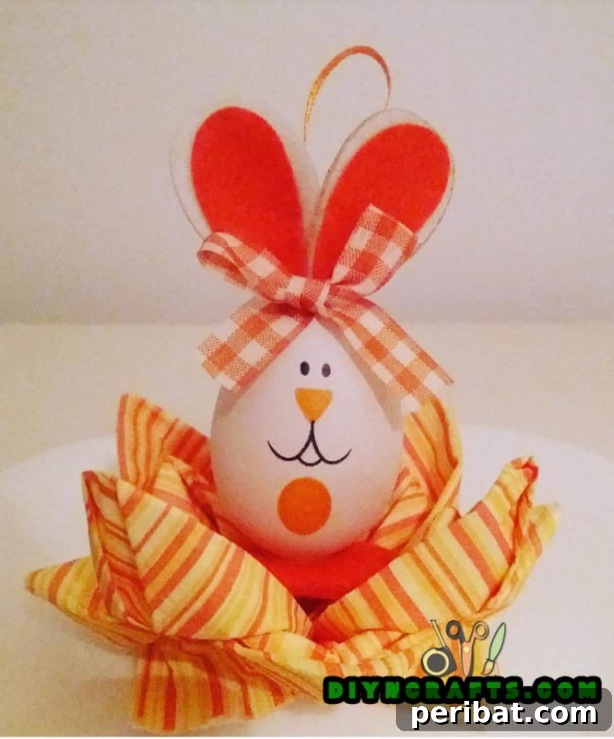 Sweet and Simple Easter Table Decor 11 Finished paper napkin flower with a decorative bunny Easter egg nestled in the center, set on a plate.