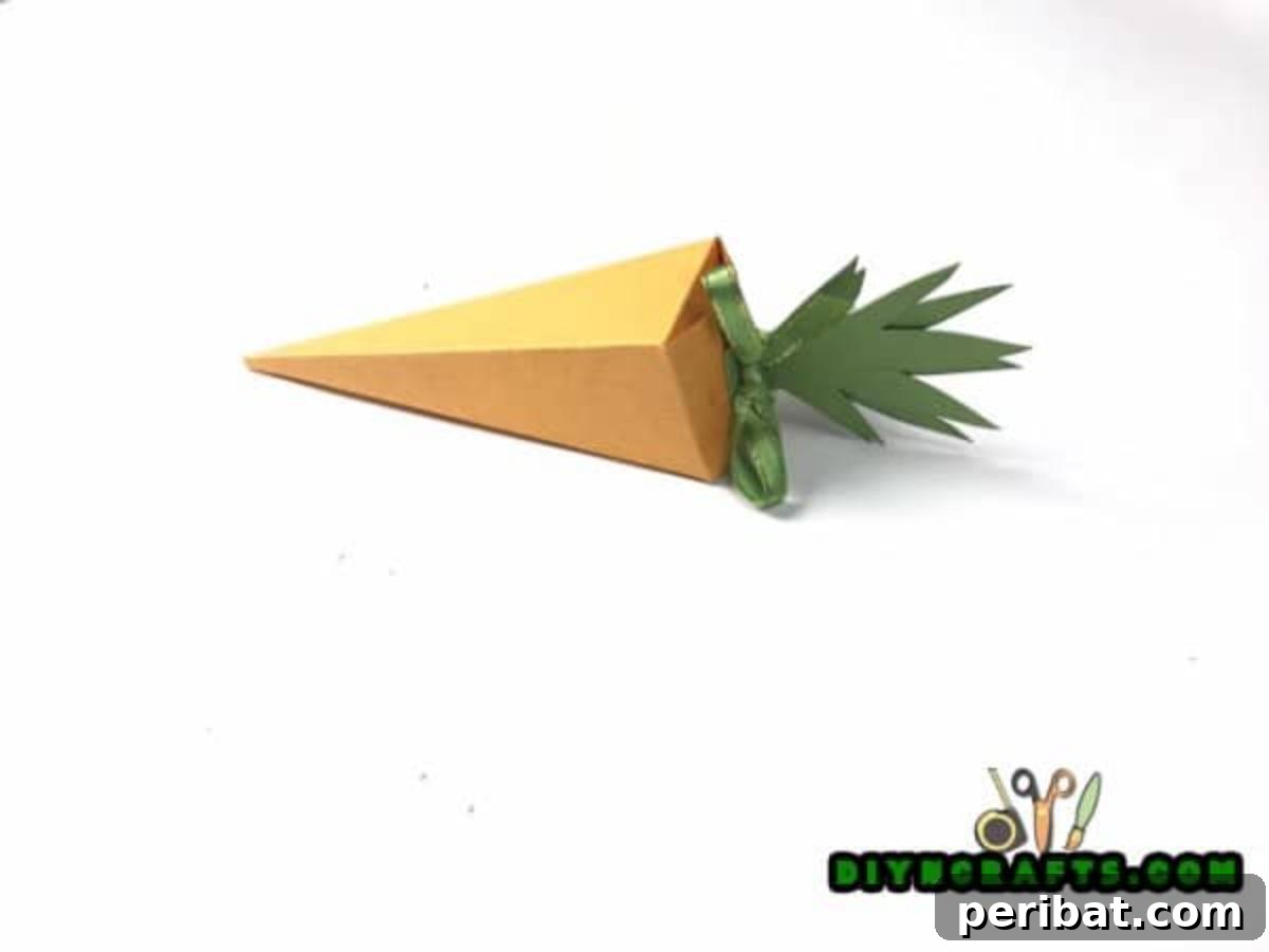 Simple Easter Carrot Box Craft Video 6 Attach green paper tops and tie with ribbon to complete and close your handcrafted Easter carrot box, perfect for spring treats.