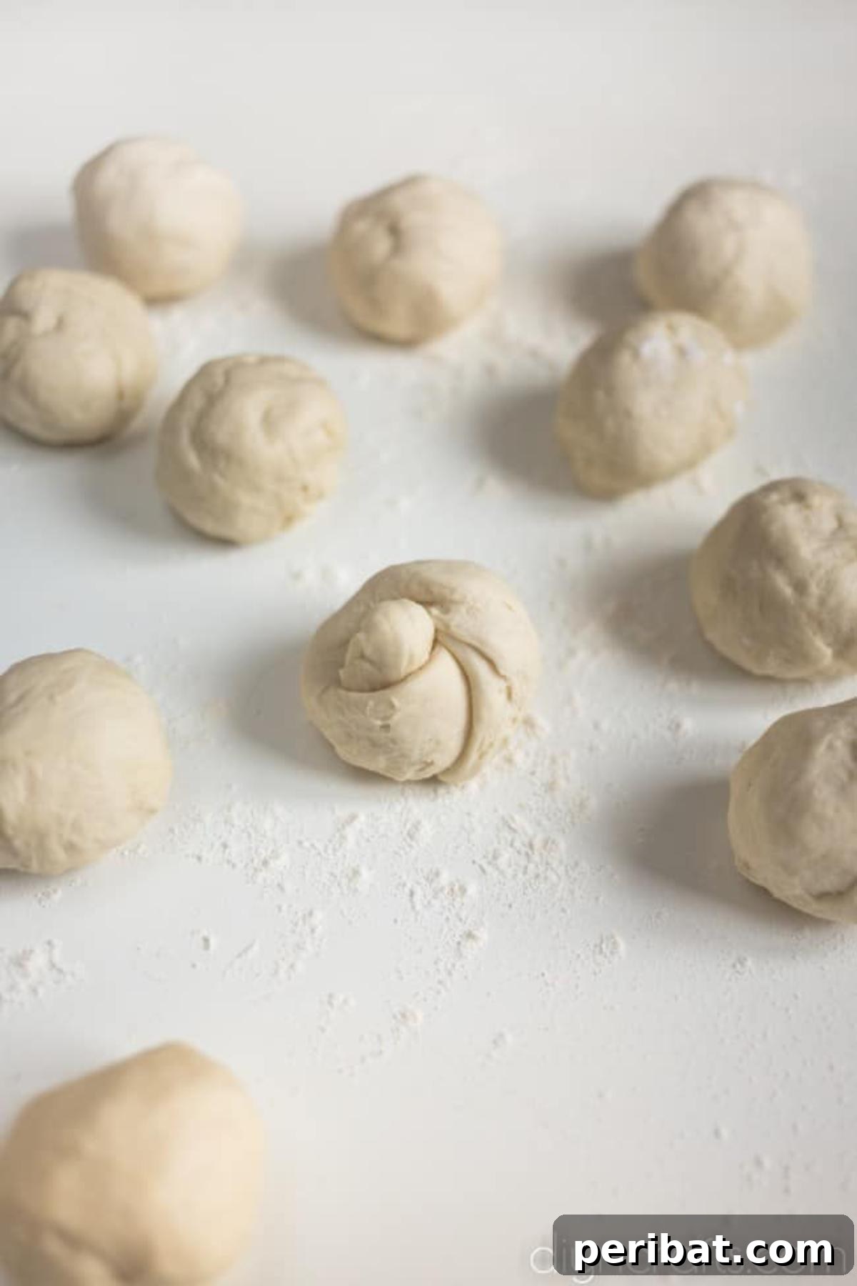 Pull-Apart Pepperoni Garlic Knots: Pure Appetizer Perfection 4 Small balls of pizza dough tied into knots on a floured surface.