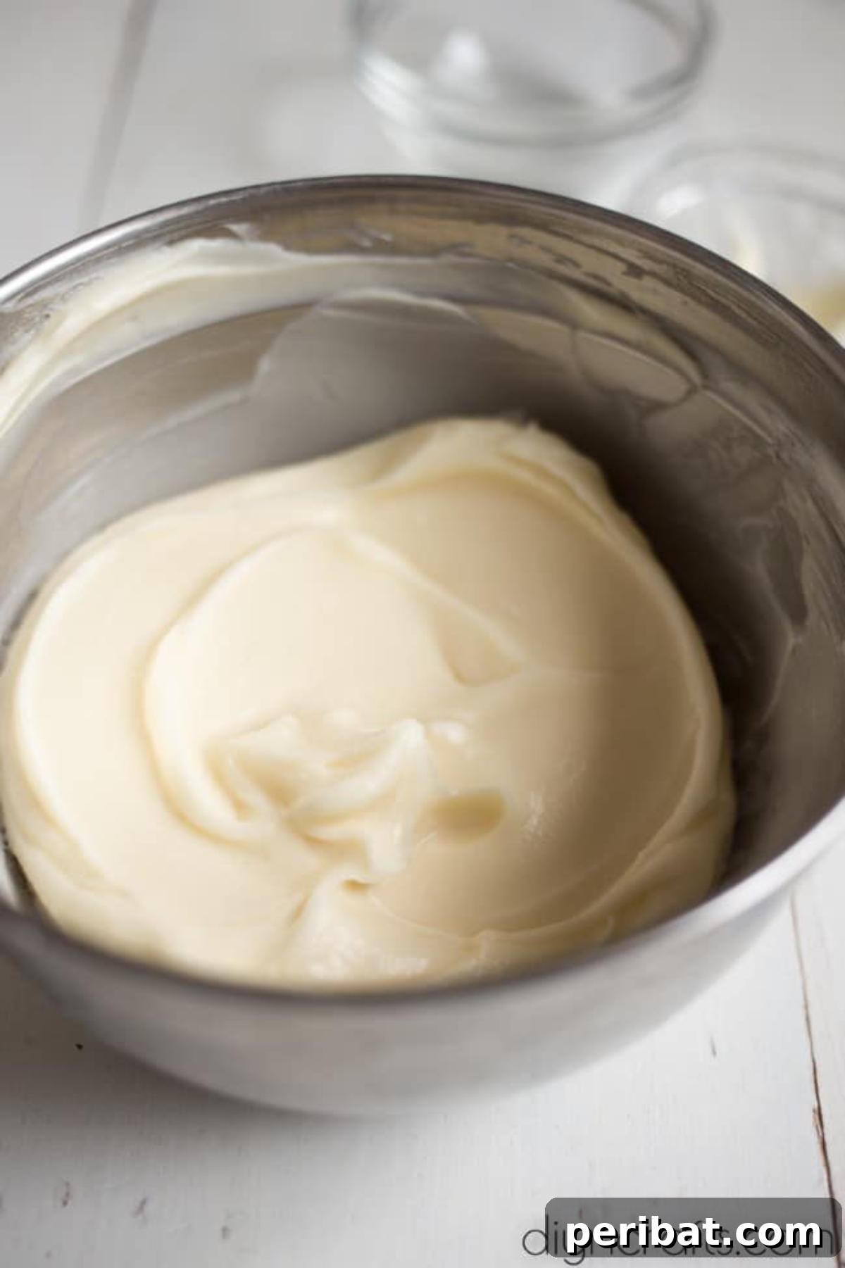Hem Şirin Hem Lezzetli Paskalya Tavşanı Pastası Tarifi 5 A bowl of freshly prepared, smooth cream cheese frosting, ready to be spread onto the Easter Bunny Cake. This homemade frosting promises a rich and tangy complement to the sweet cake.
